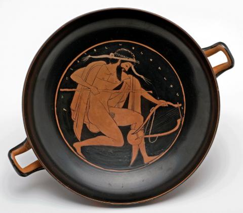 Red-figured cup A reveller running with a lyre and a staff (inside); a symposium scene and a battle (outside) Athens, c.520 - 500 BC